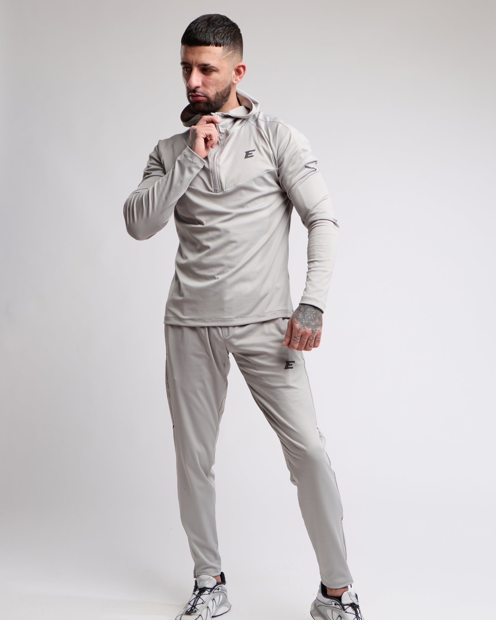 Man wearing a gray tracksuit with a brand logo on a white background