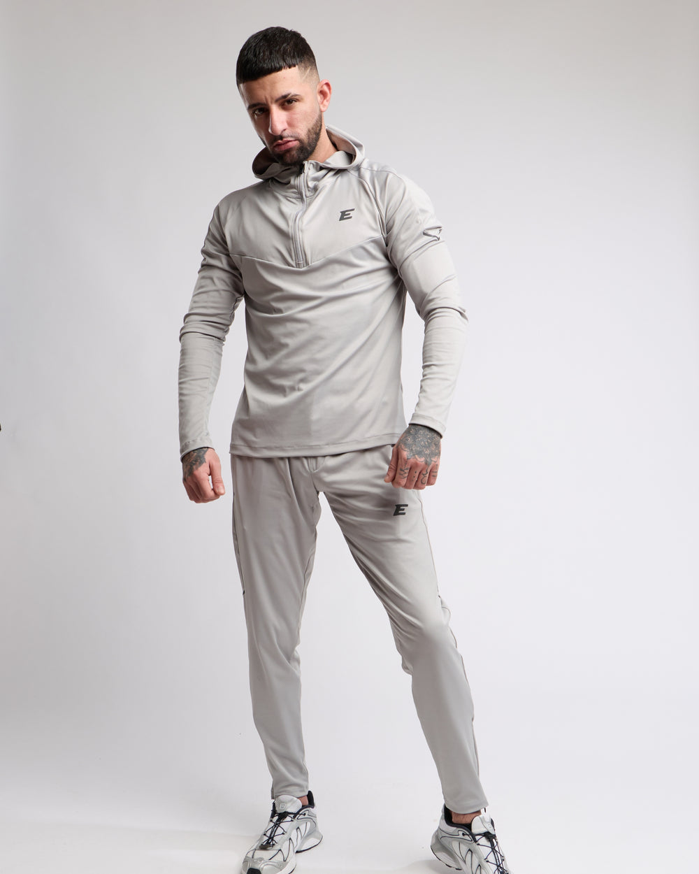 Man wearing a gray tracksuit with a brand logo on a white background