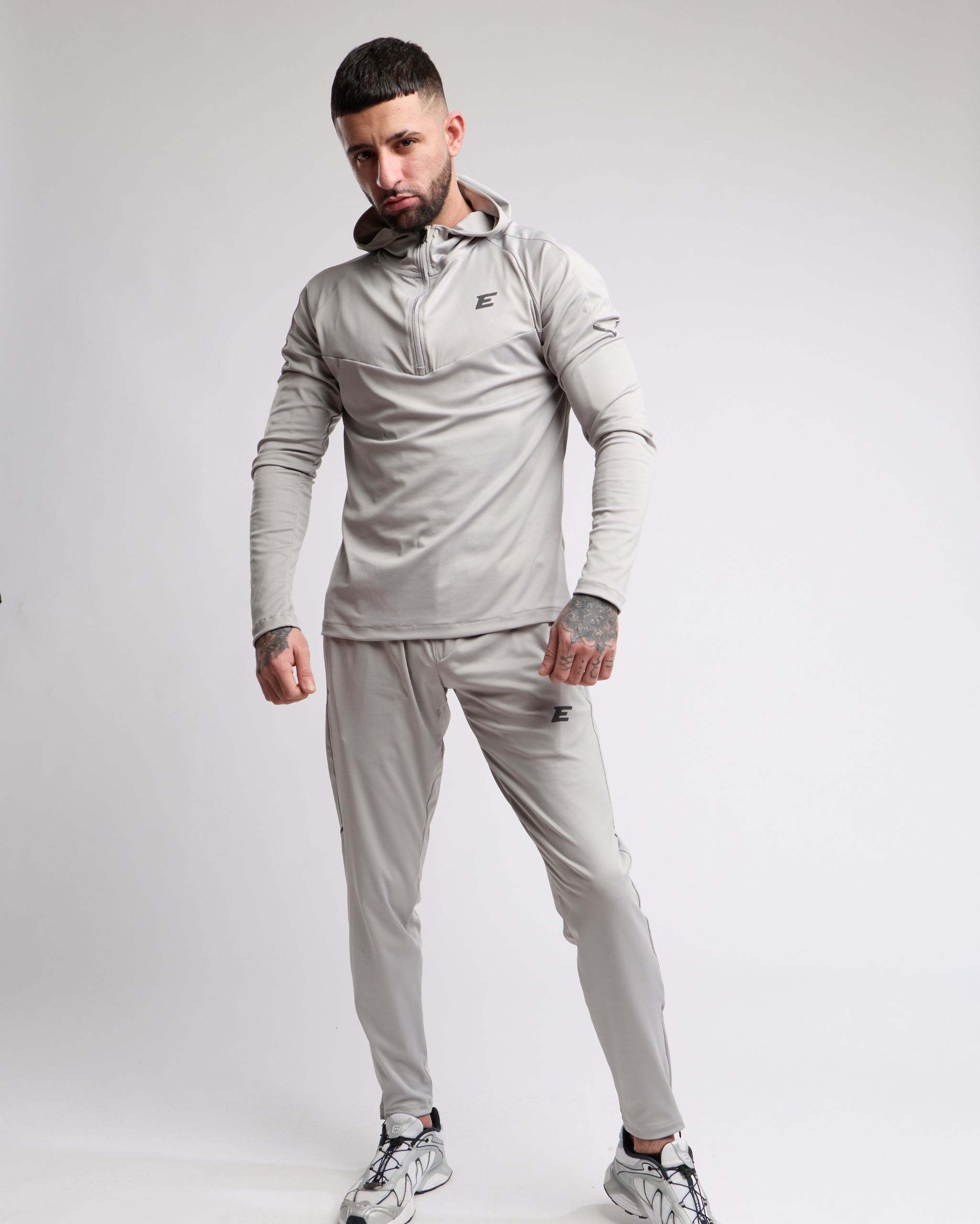 Man wearing a gray tracksuit with a brand logo on a white background