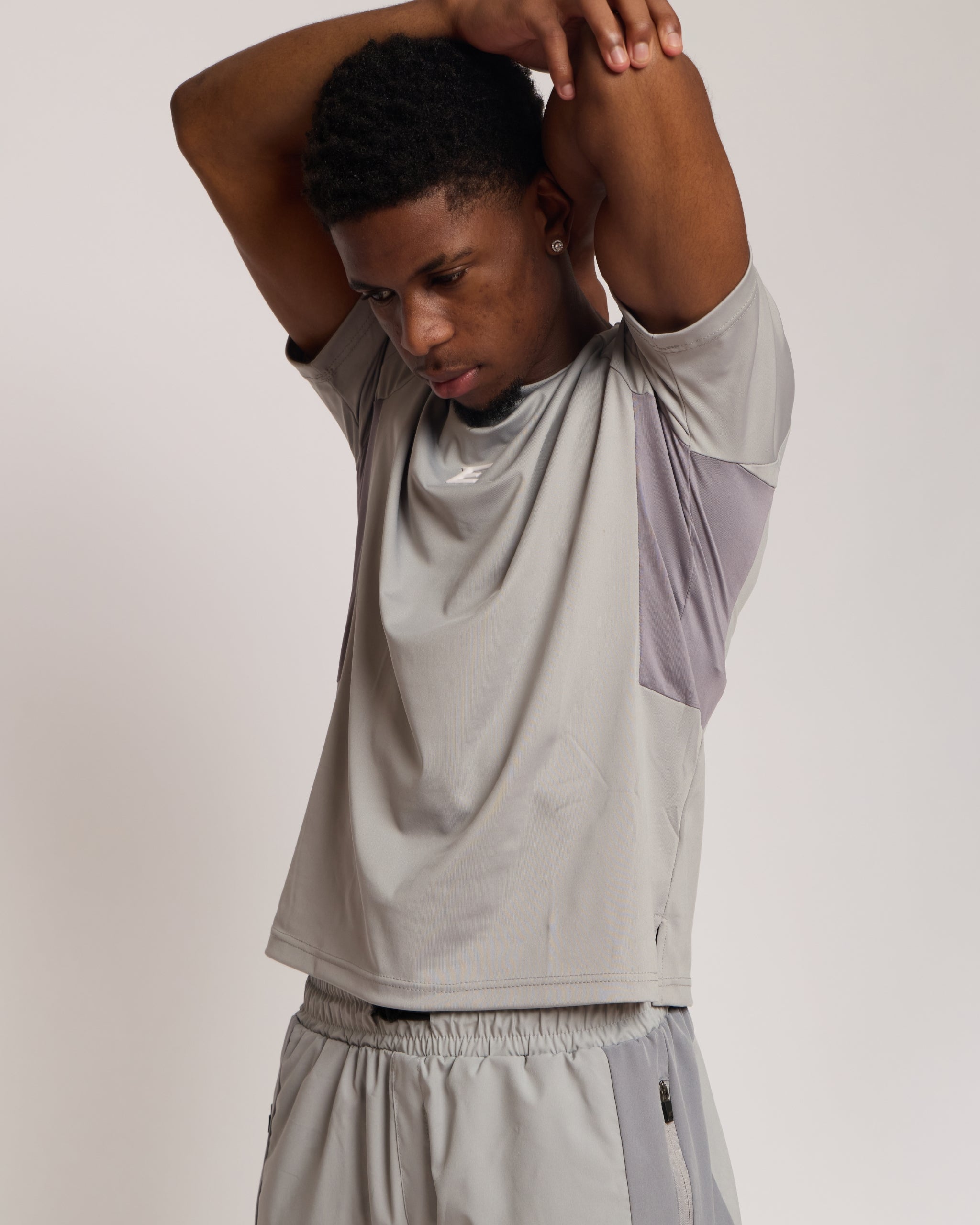 man wearing a gray athletic shirt with an elegante logo on a plain background