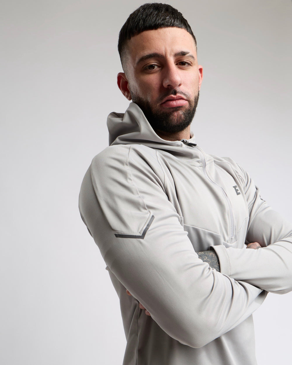 Man wearing a light gray tracksuit hoodie with a neutral background