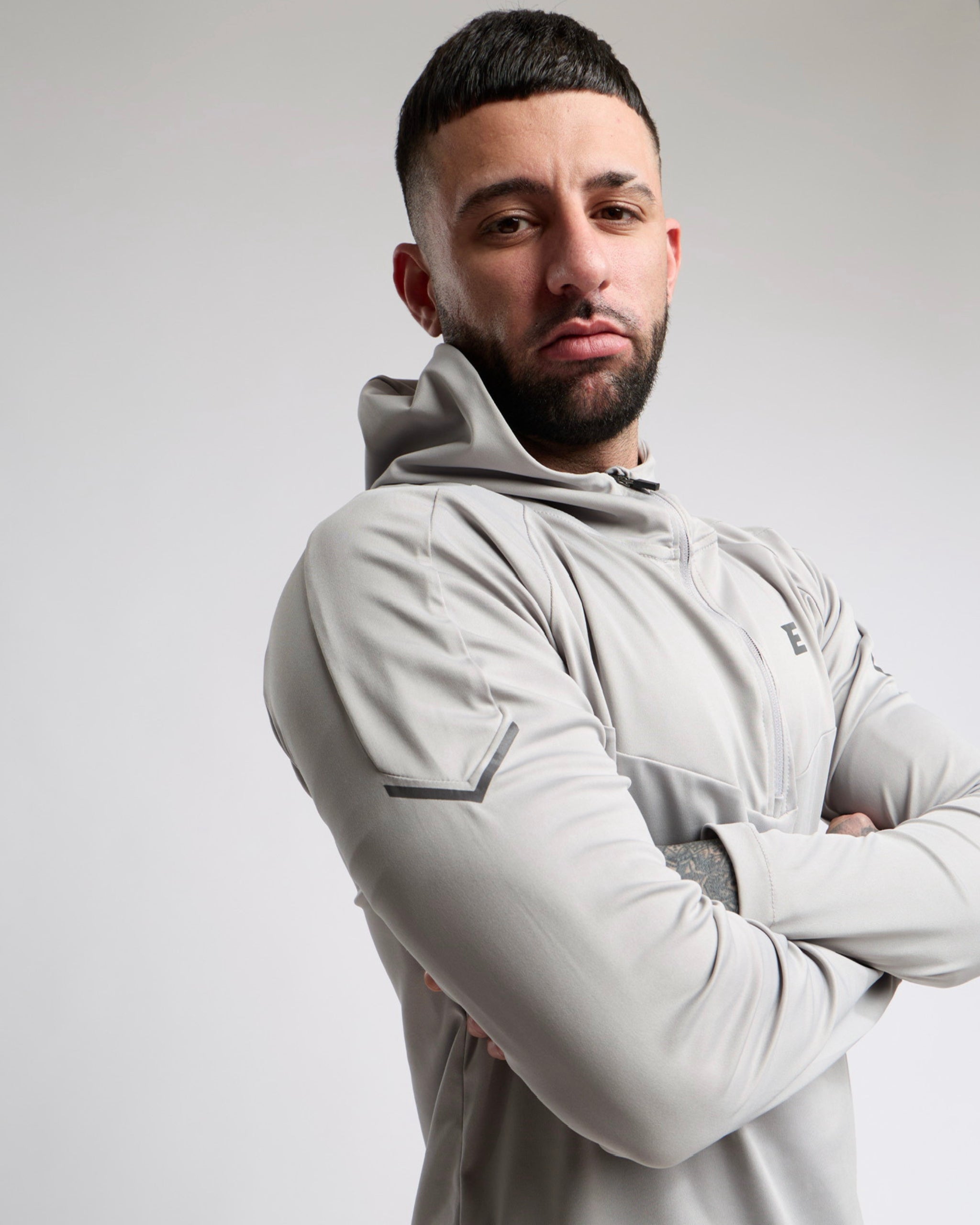 Man wearing a light gray tracksuit hoodie with a neutral background