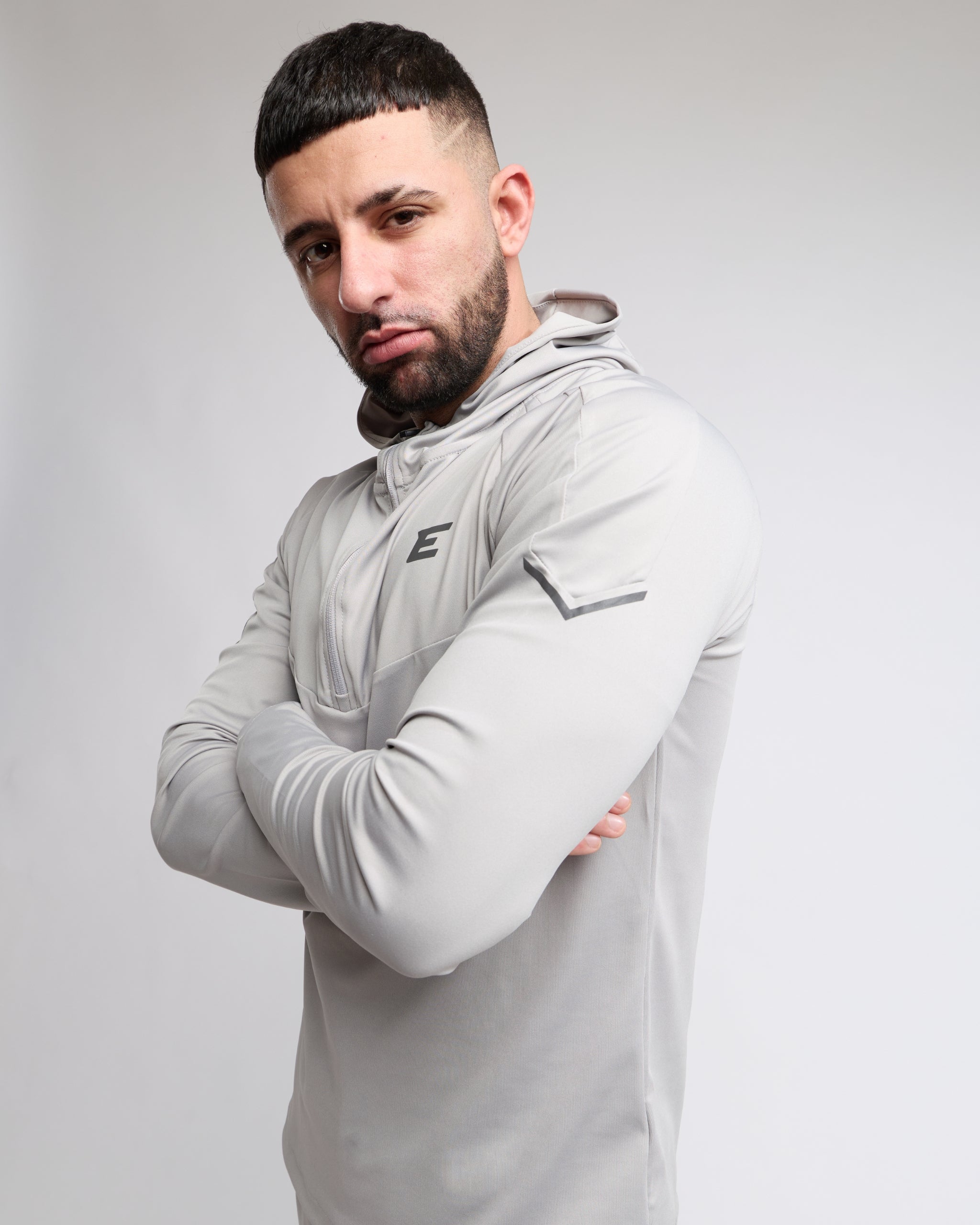 Man wearing a gray hoodie with a brand logo on a white background