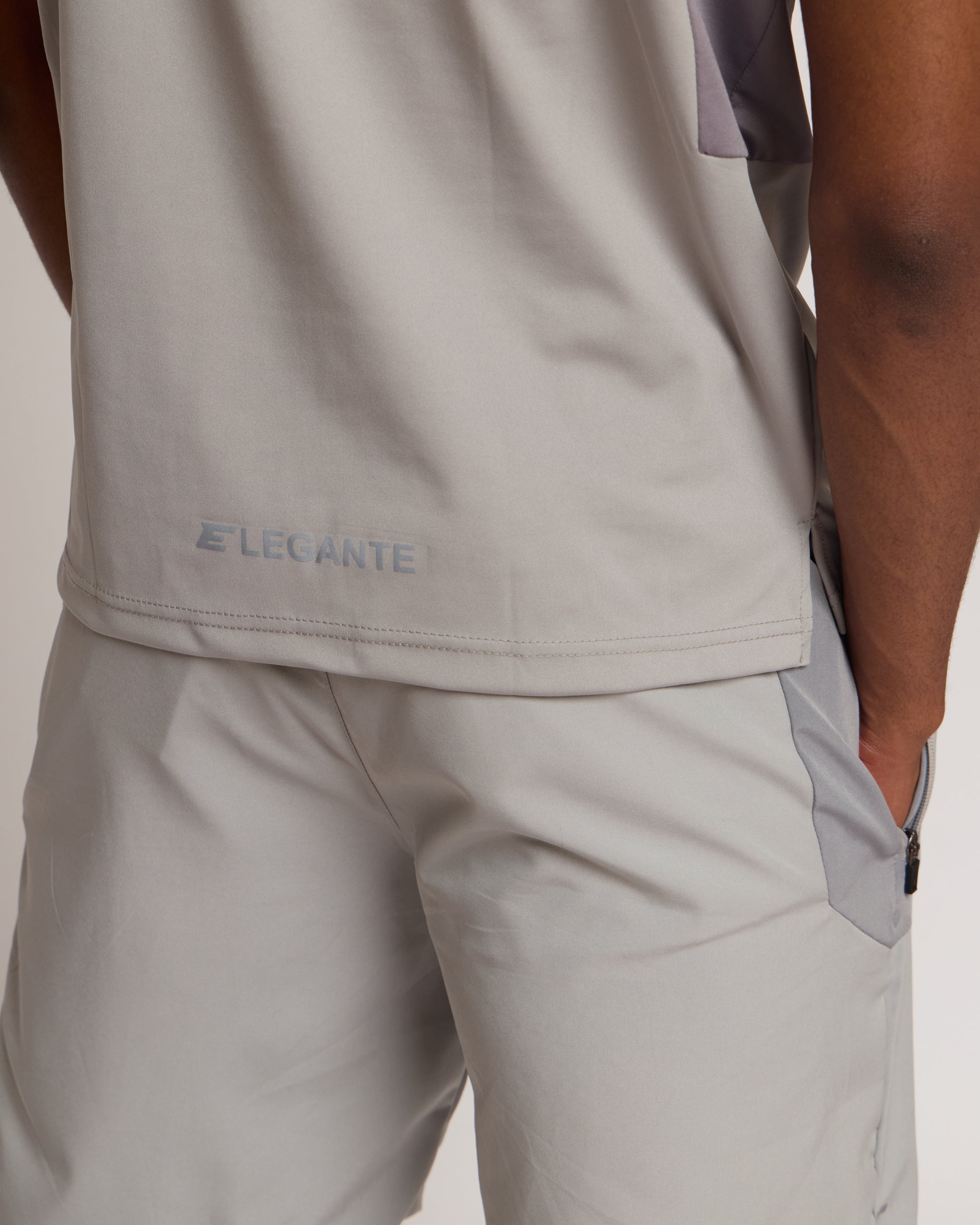 Man wearing a gray athletic shorts and t-shirt outfit with an 'E' logo on a grey background