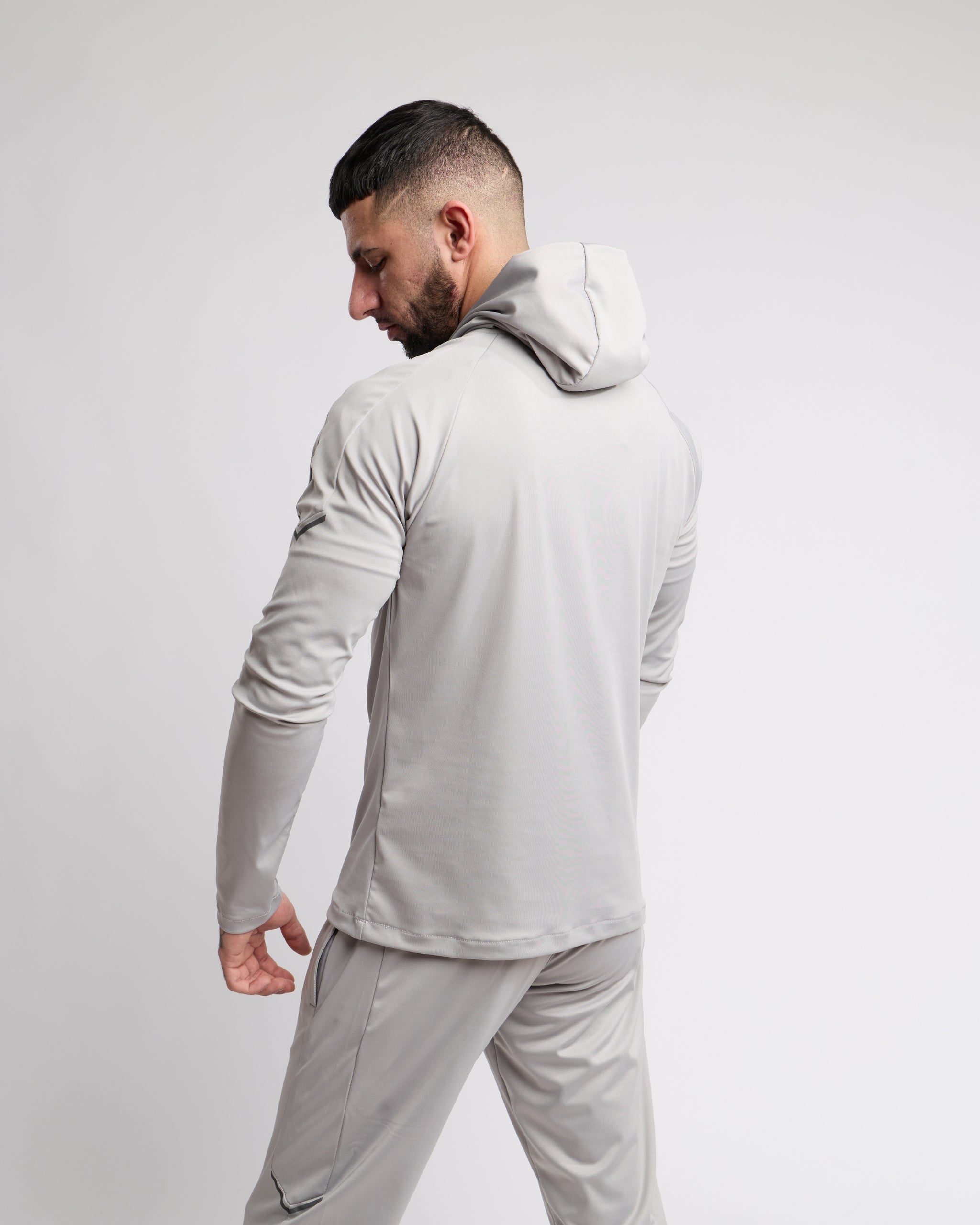 Man wearing a light gray tracksuit against a white background