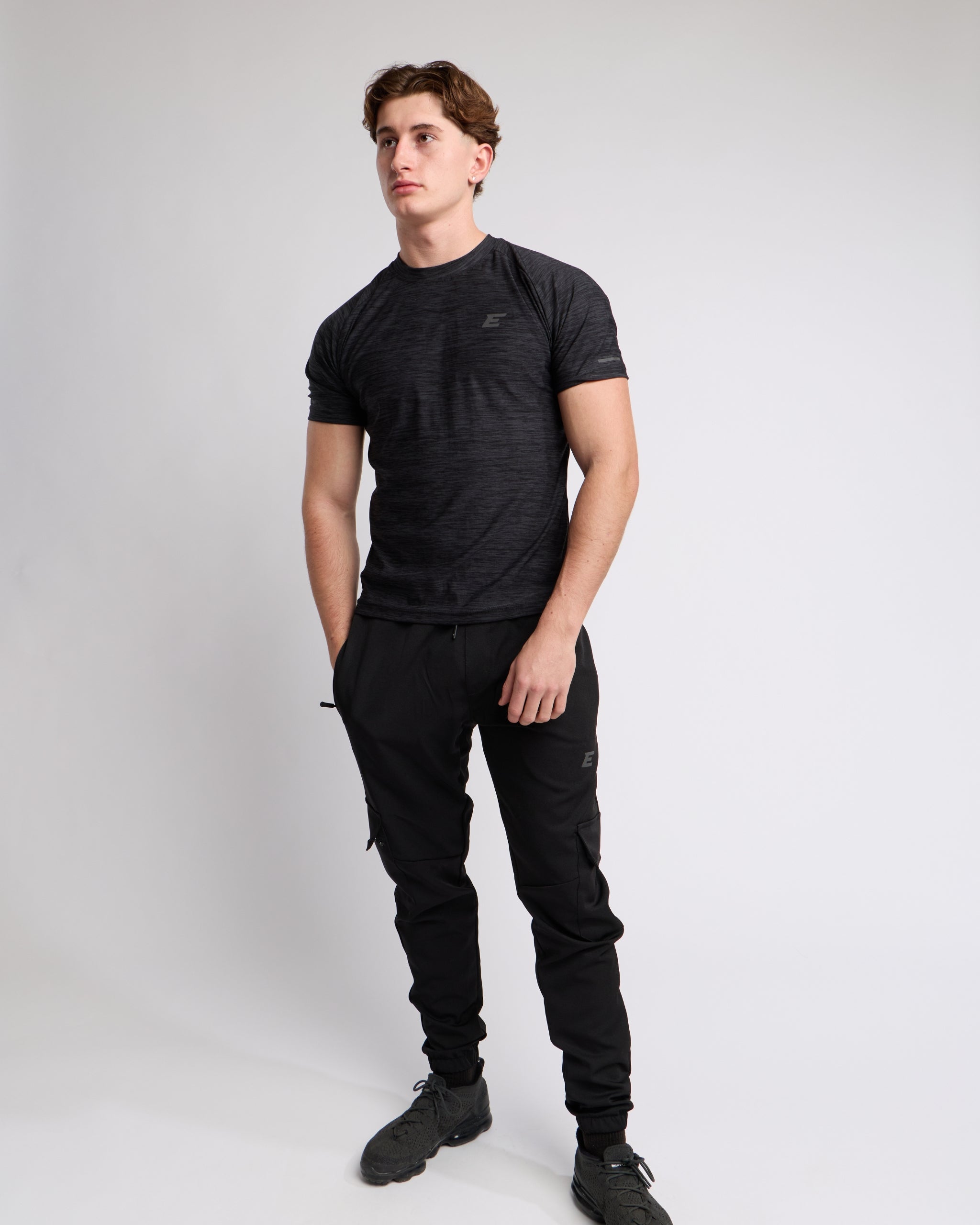 Man wearing a black athletic t-shirt and joggers with a elegante london logo on a light gray background