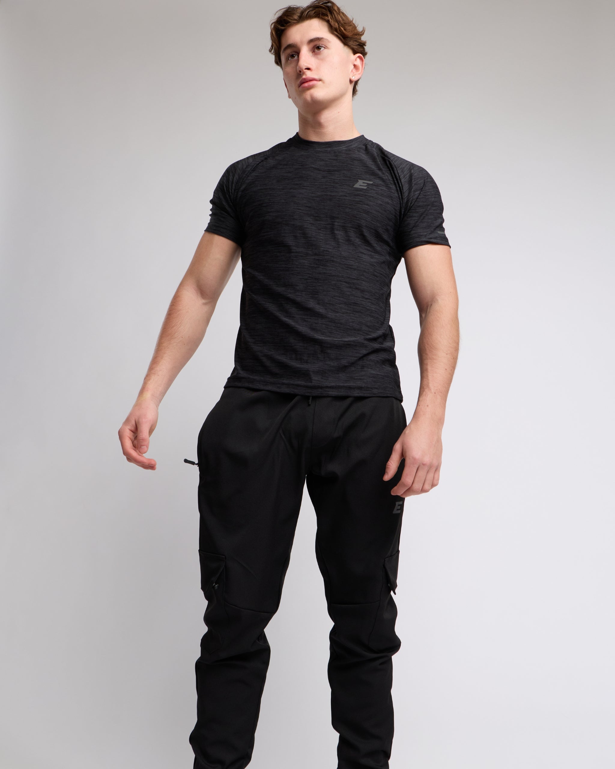 Man wearing a black athletic t-shirt and joggers with a elegante london logo on a light gray background