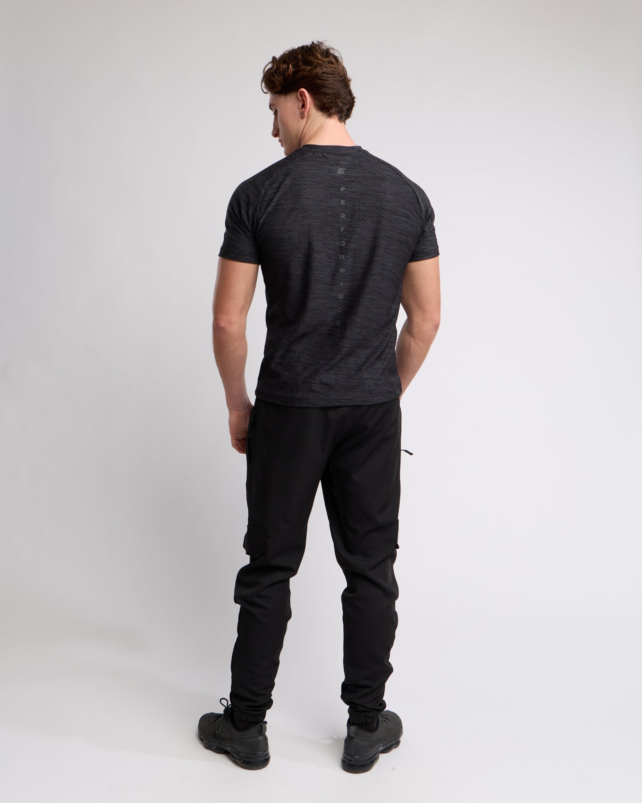 Man wearing a black athletic t-shirt and joggers with a elegante london logo on a light gray background