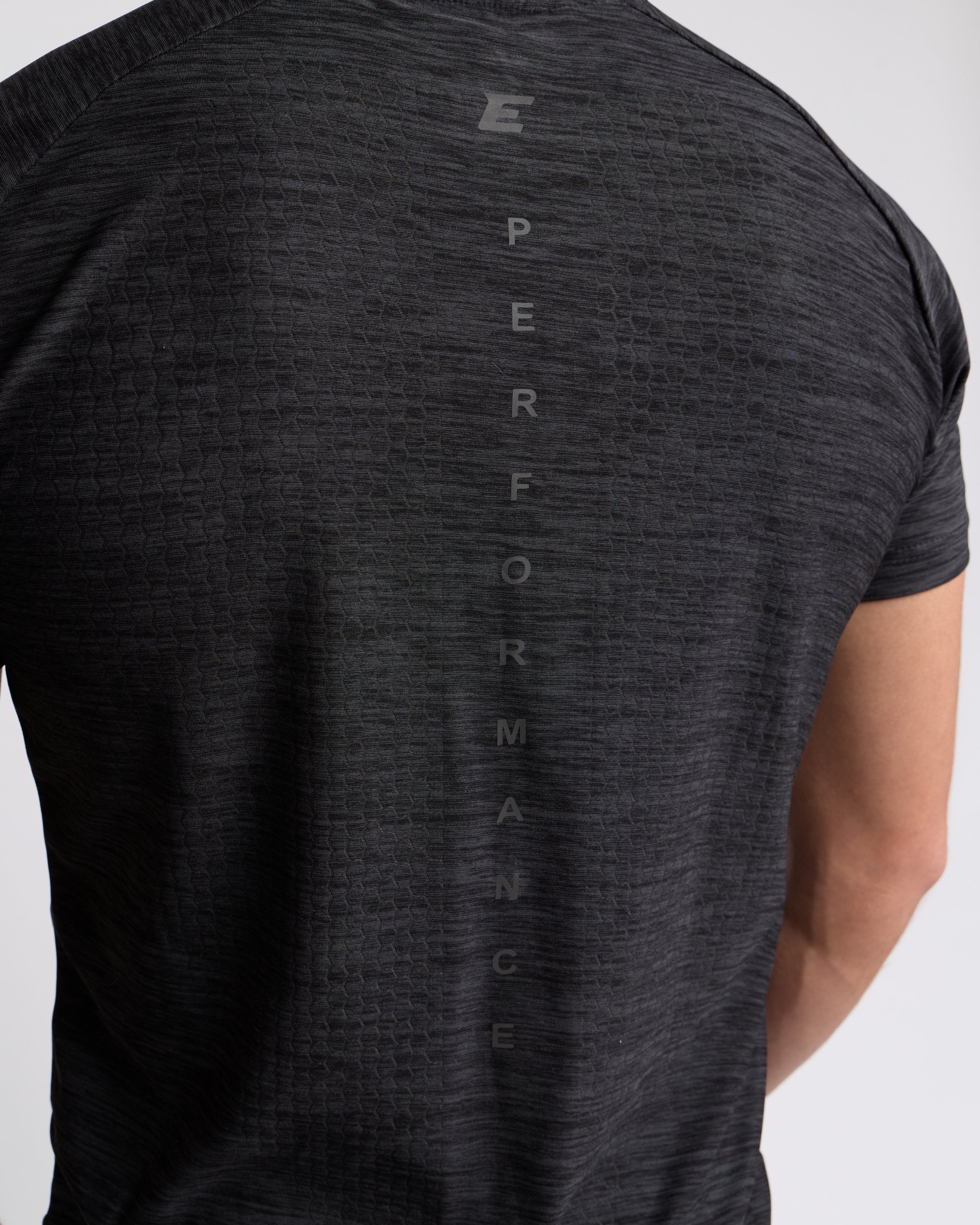 Dark gray t-shirt with 'PERFORMANCE' text on the back against a light gray background