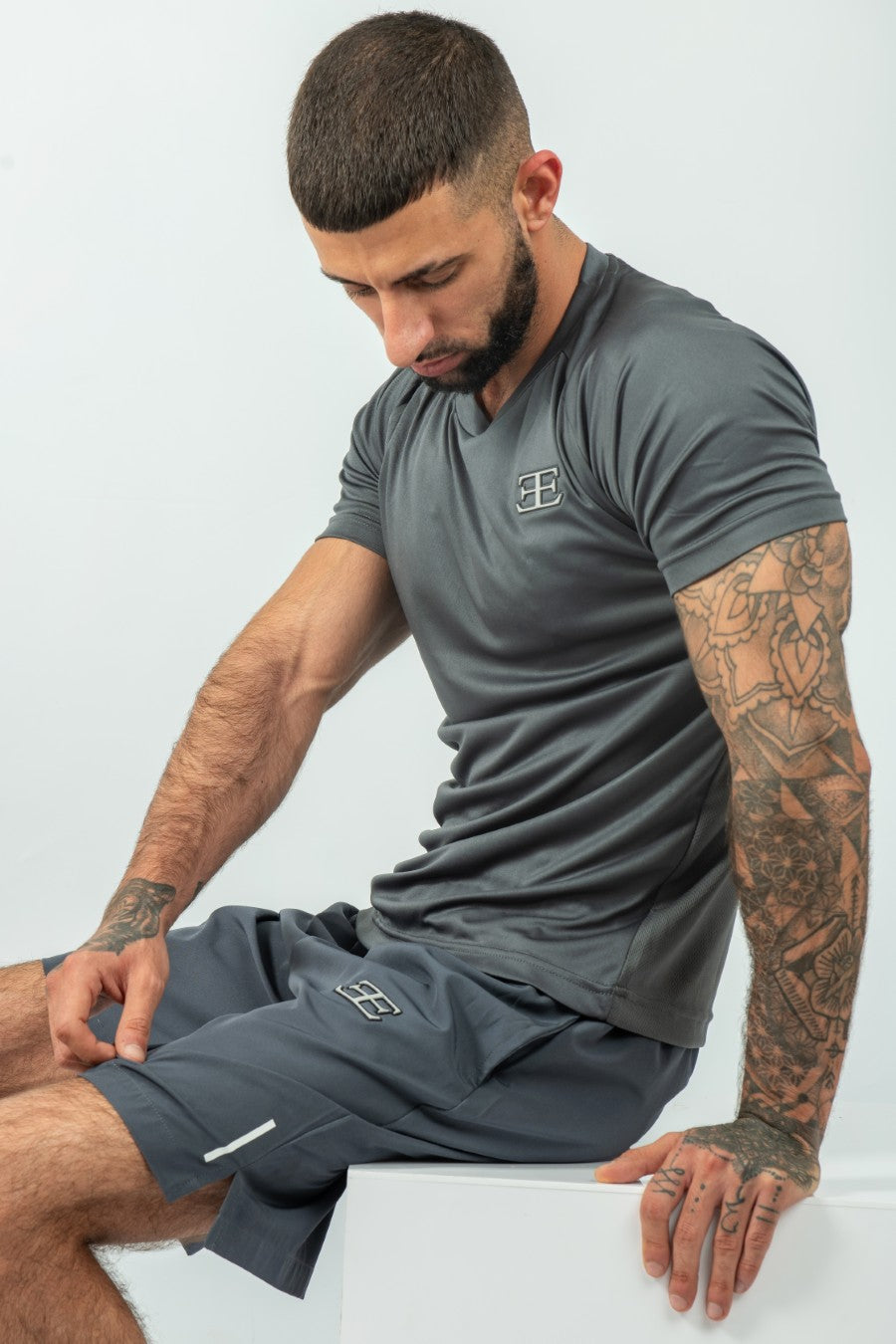 Man wearing a gray athletic outfit with a logo on a white background