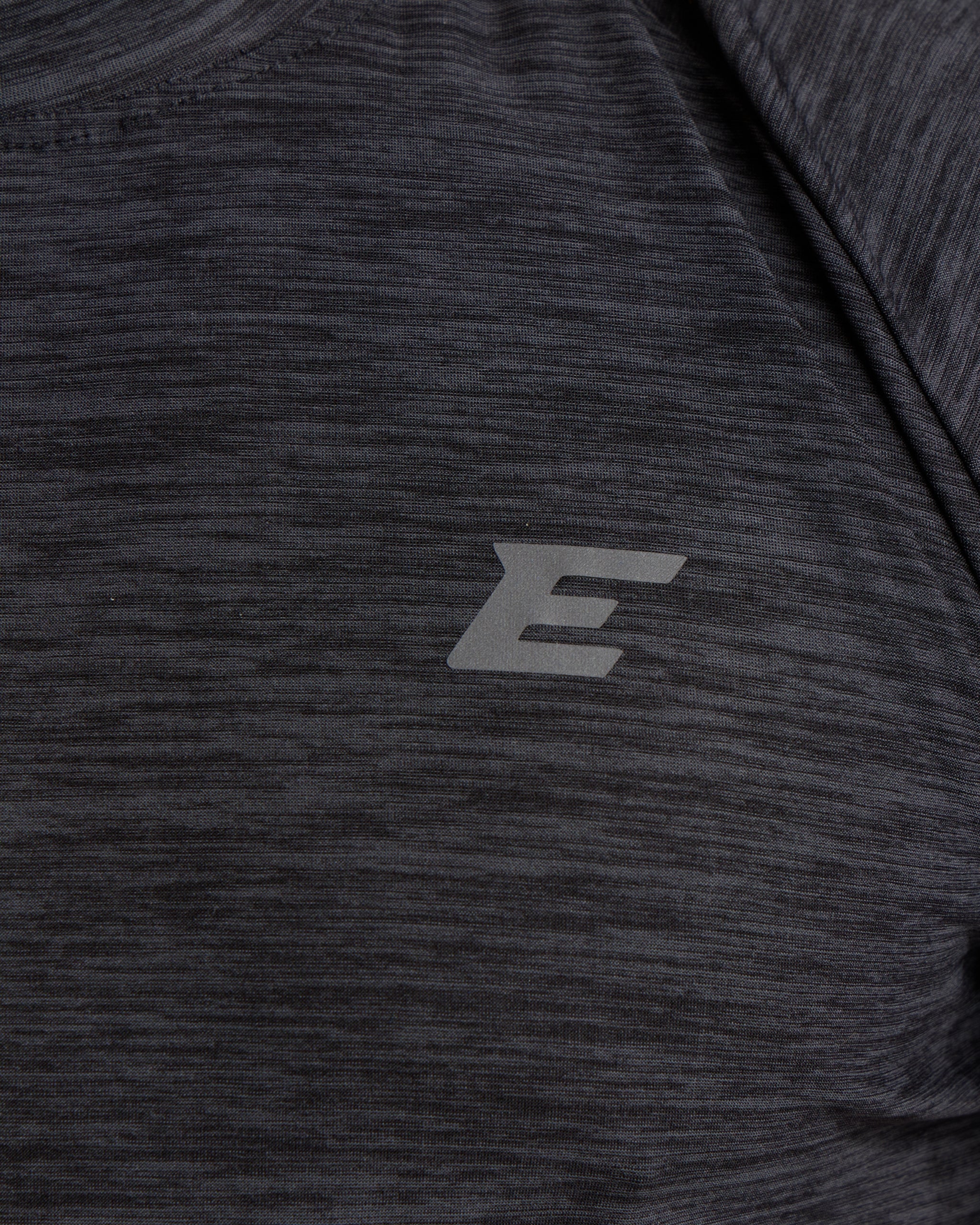 Close-up of a dark gray athletic shirt with a E logo on the chest.