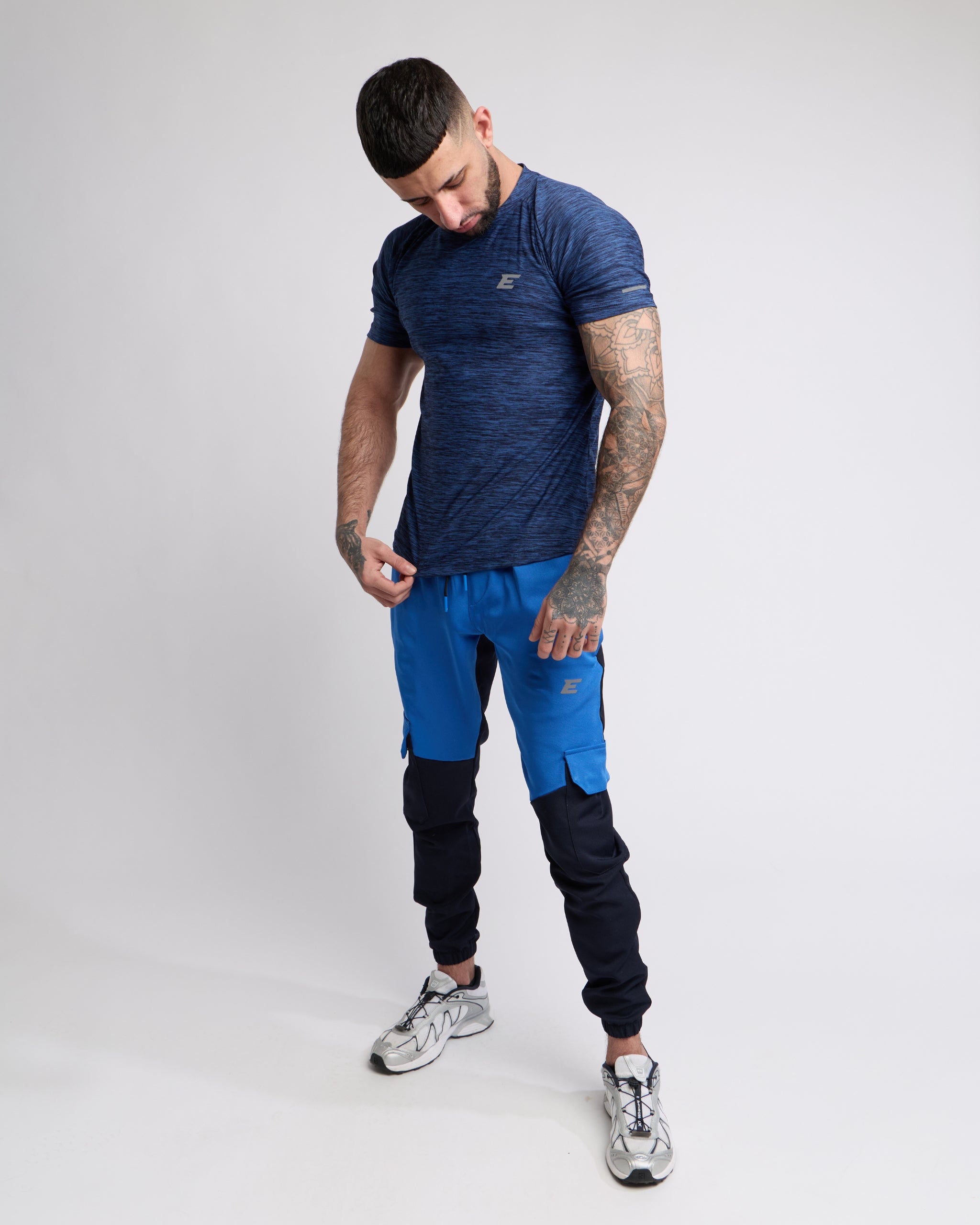 Man wearing a blue athletic outfit with a brand logo on a white background