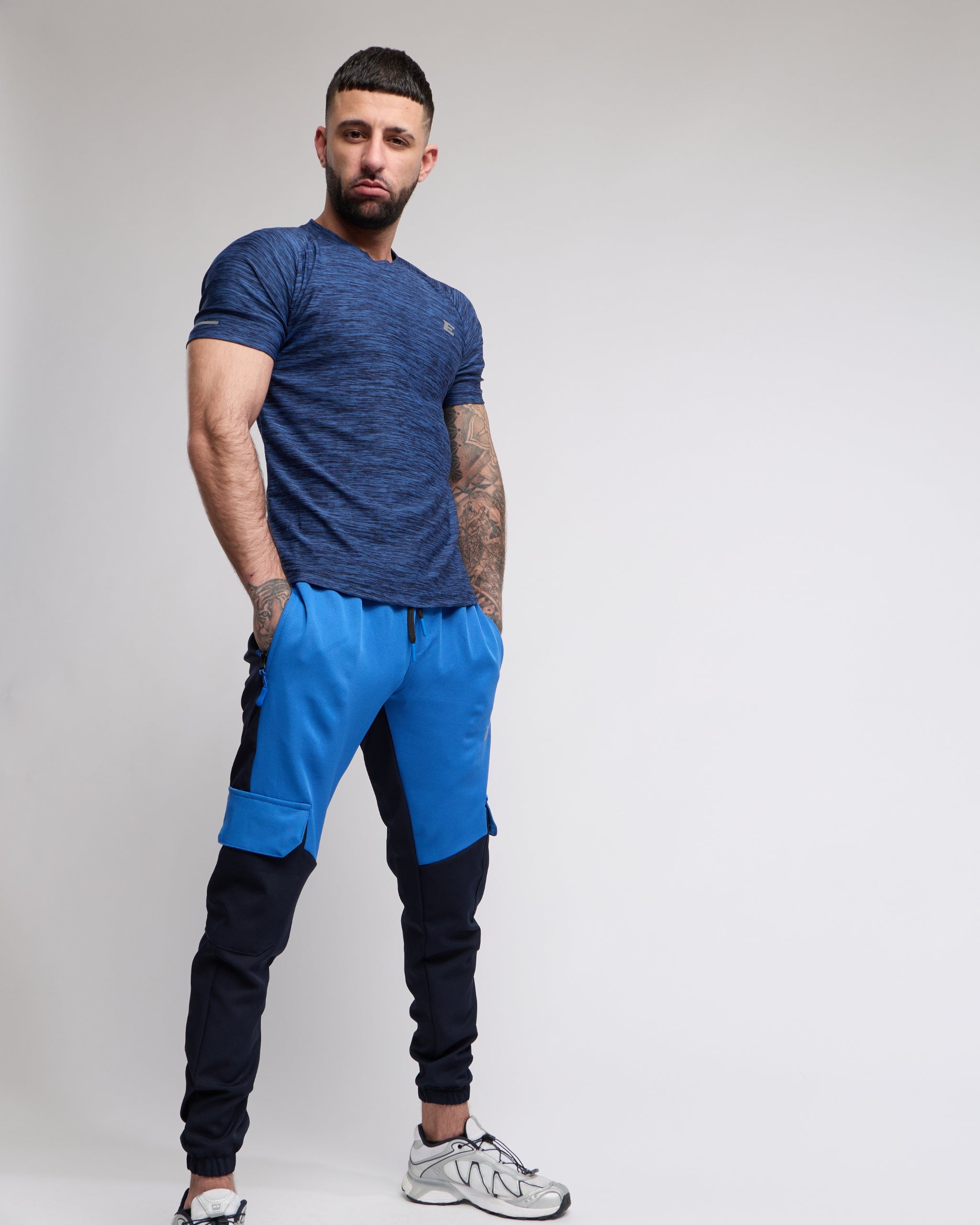 Man wearing a blue athletic outfit with black pants on a plain background