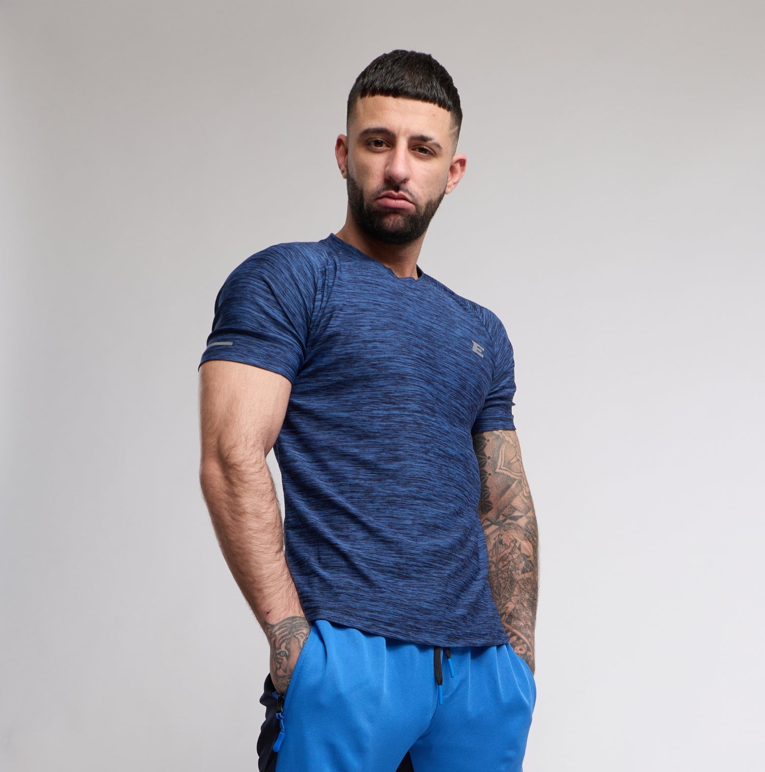 Man wearing a blue athletic outfit with black pants on a plain background