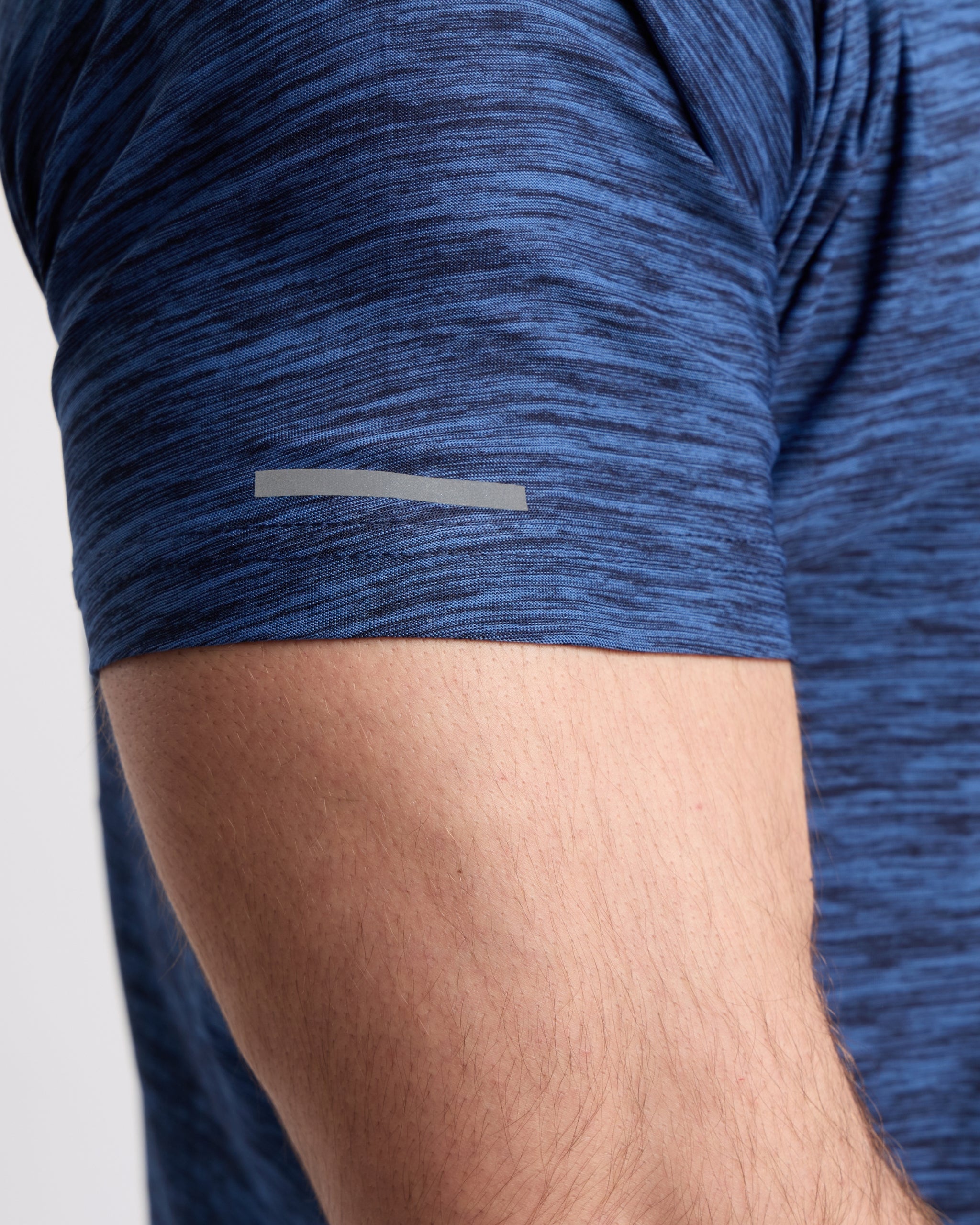 Close-up of a person wearing a blue athletic tshirt with a small reflective on the sleeve.