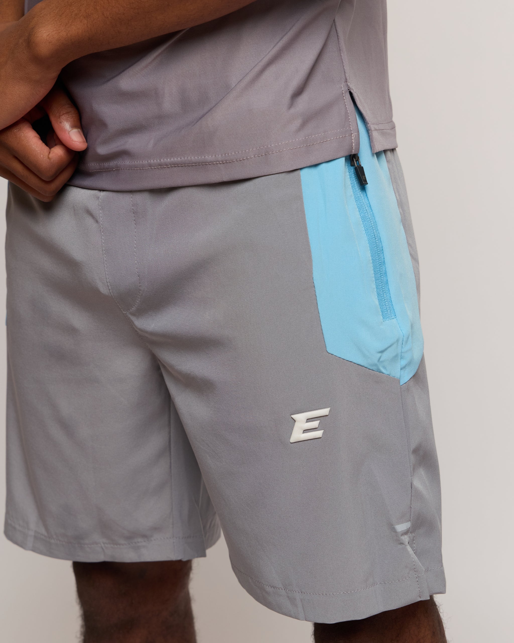 Gray shorts with a blue pocket and elegante logo on a neutral background