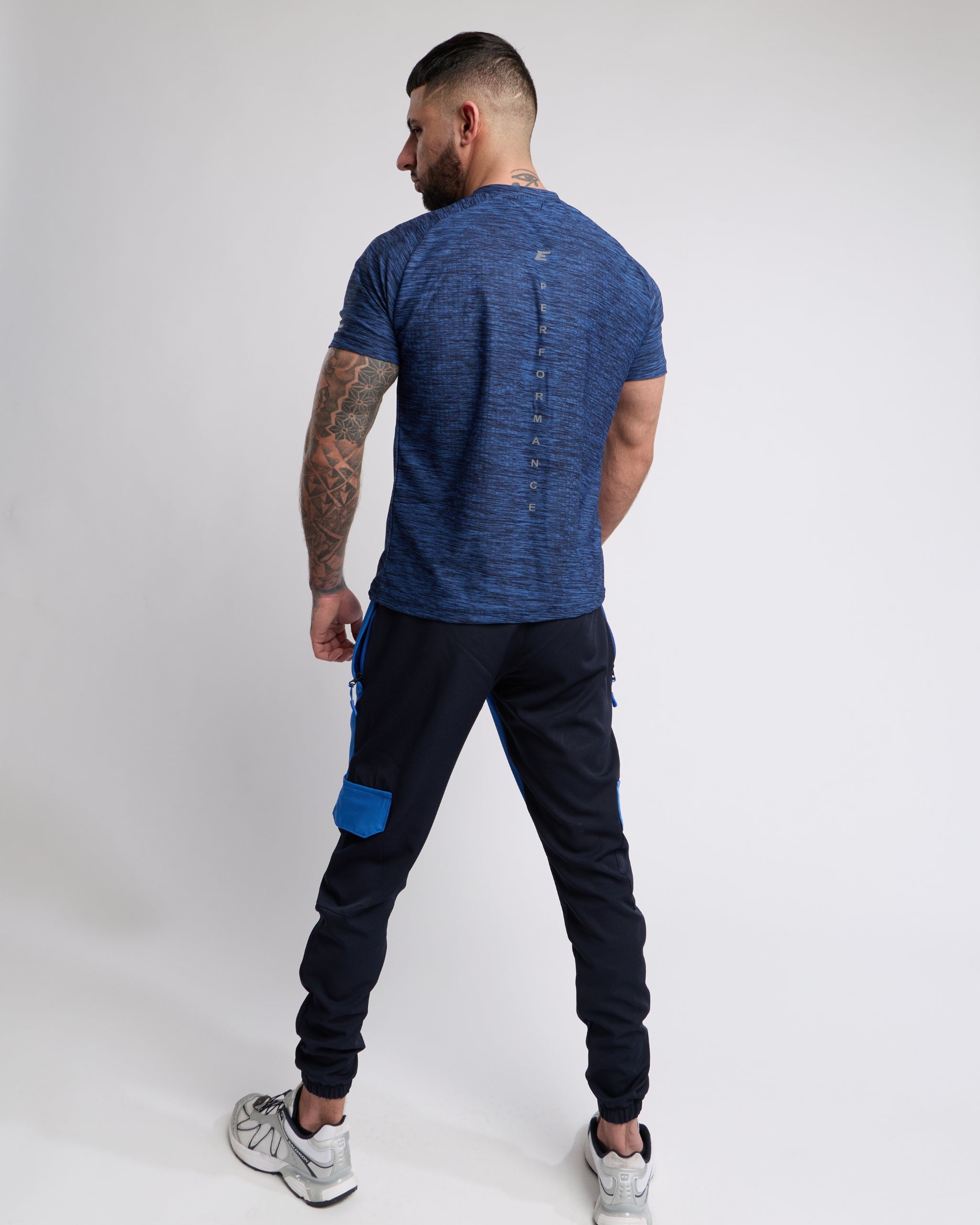 Man wearing a blue t-shirt and black pants with blue accents on a white background