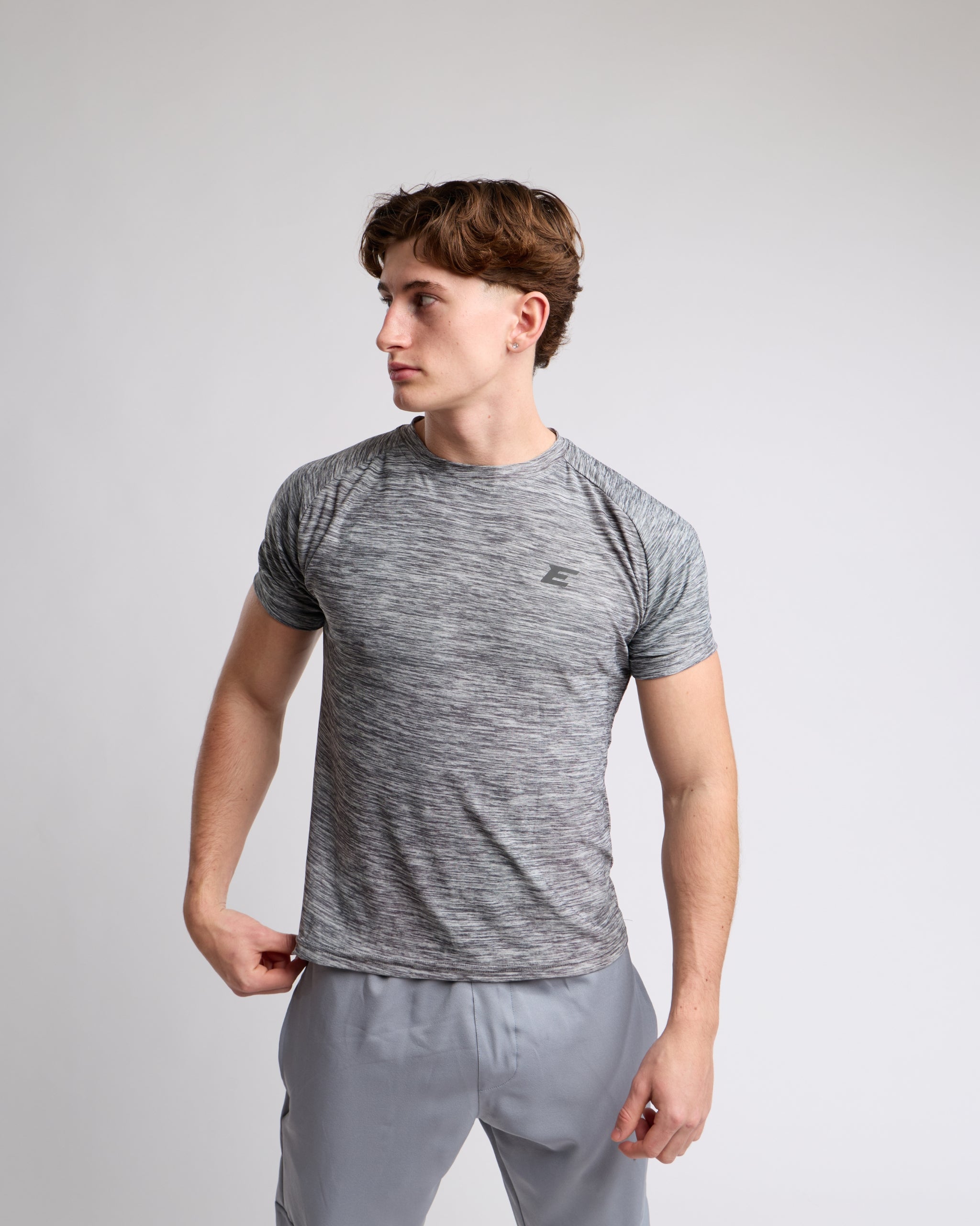 Man wearing a gray athletic tshirt with a elegante london logo on a light gray background