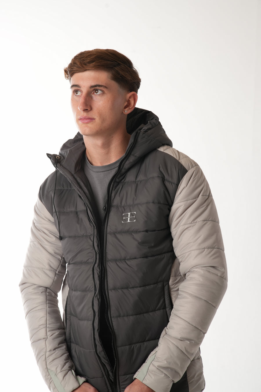 Person wearing a gray and beige puffer vest on a white background