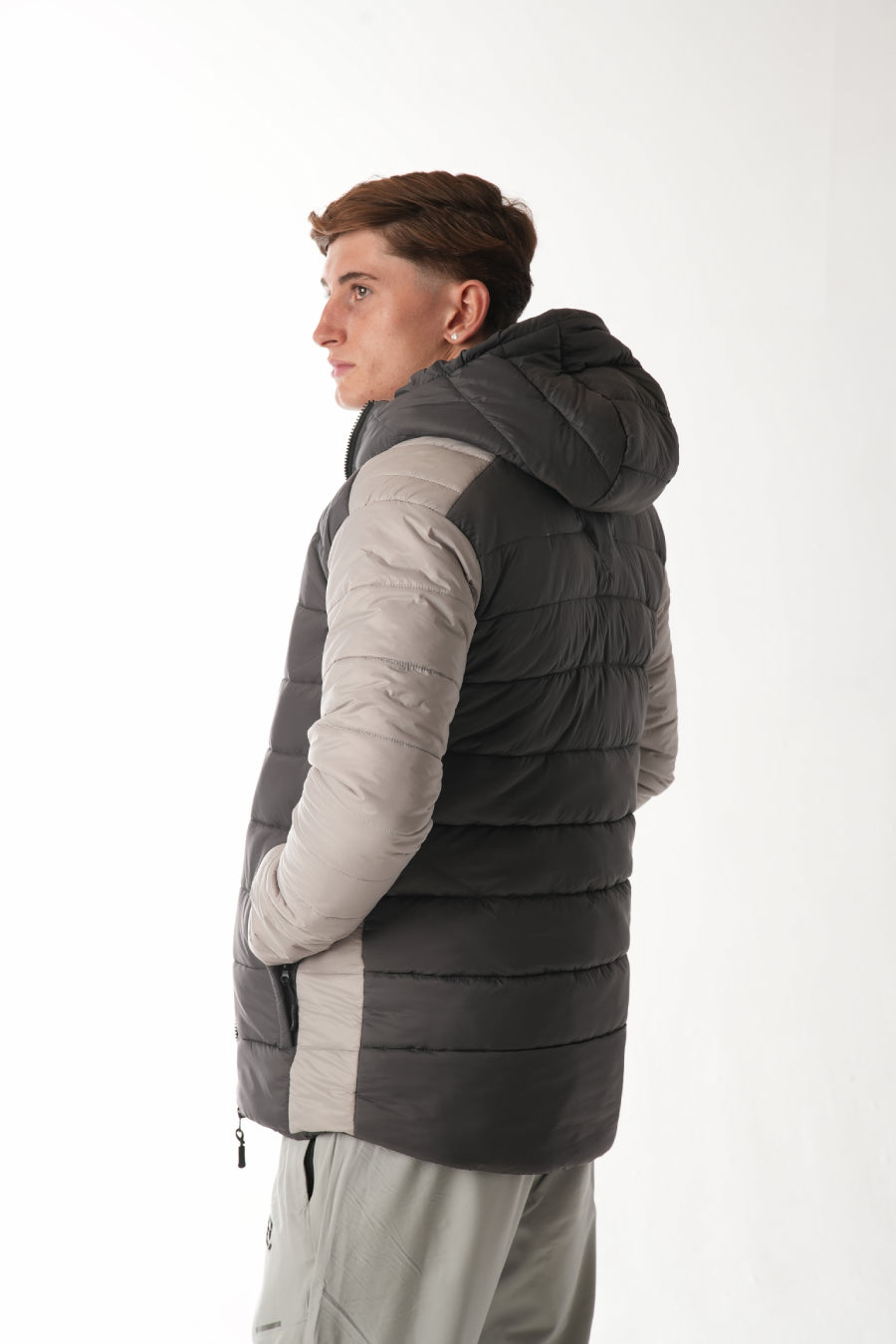 Person wearing a gray and beige puffer vest on a white background