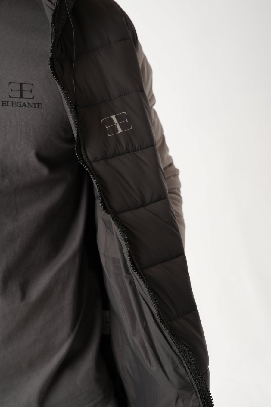 Close-up of a dark gray jacket with elegante brand logo on a white background