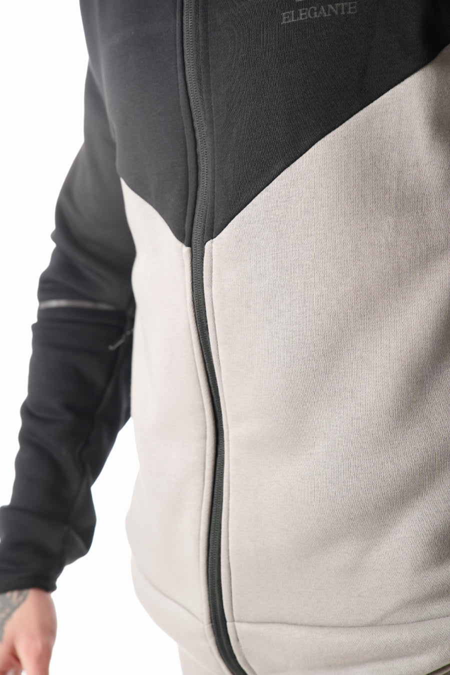 Close-up of a black and grey tracksuit jacket with 'Elegante' branding on a white background