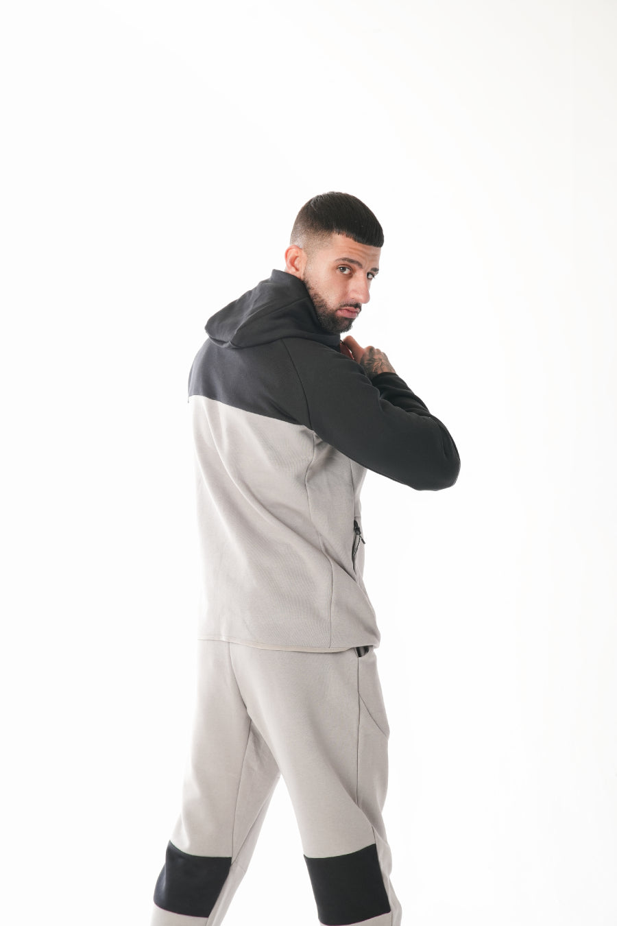 Man wearing a gray and black tracksuit on a white background