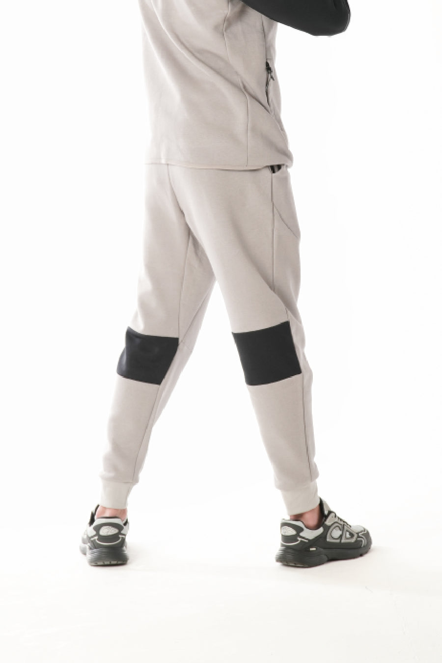 MAn wearing light gray pants with black  on a white background