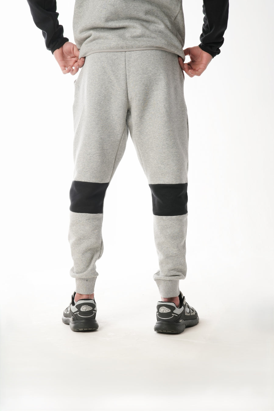 Person wearing gray jogger pants with black accents on a white background