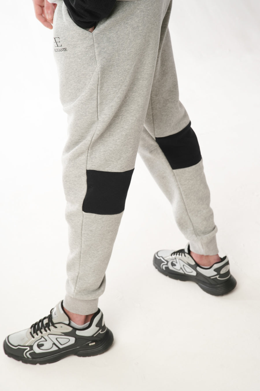 Gray sweatpants with black patches worn by a man on a white background