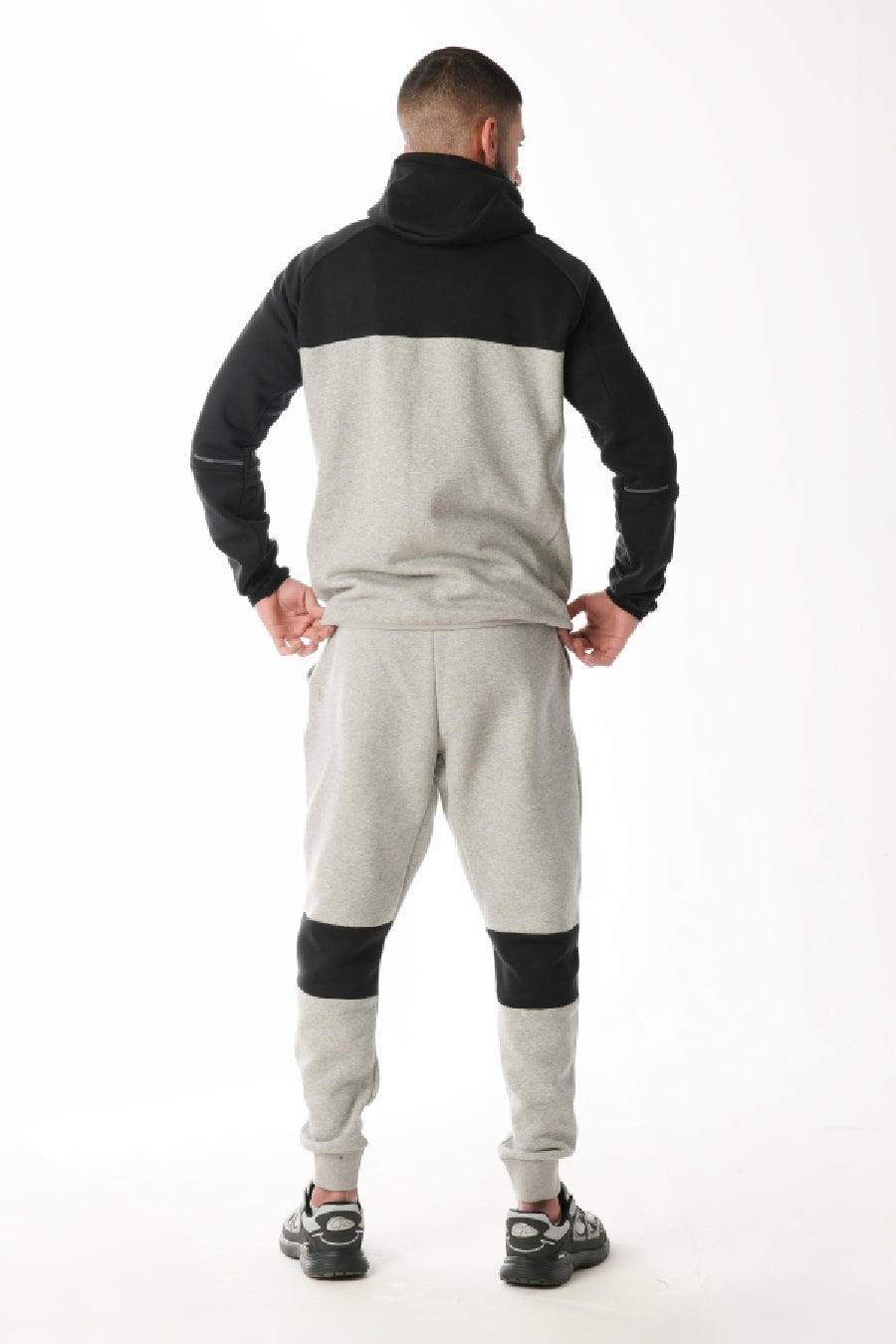 Person wearing a black and gray tracksuit on a white background