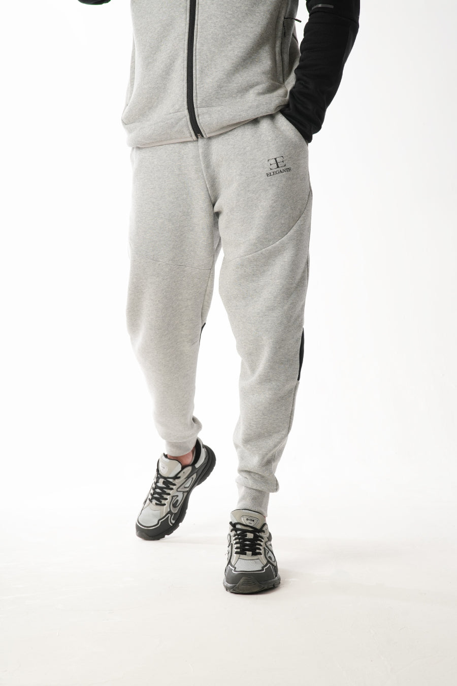 Person wearing a gray tracksuit with black accents on a white background
