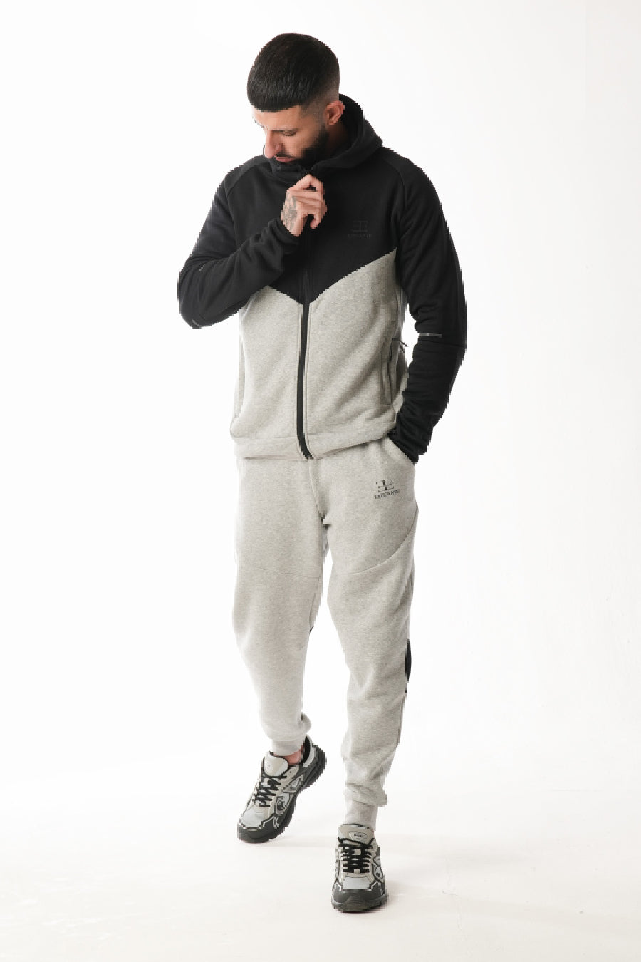 Man wearing a black and gray tracksuit on a white background