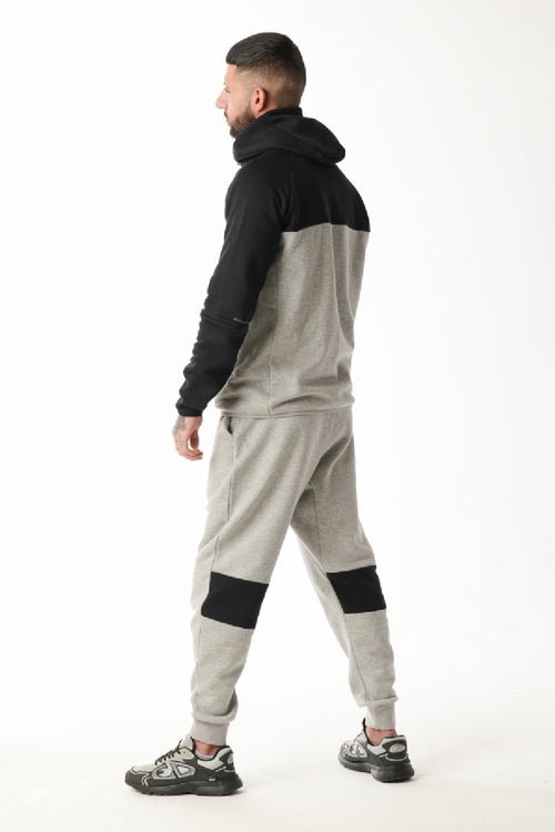 Person wearing a gray and black tracksuit on a white background