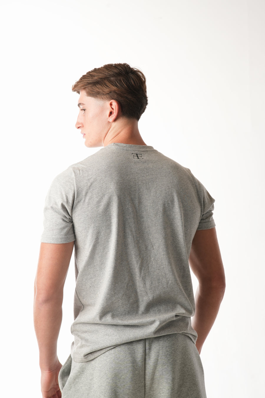 Person wearing a gray t-shirt and shorts on a white background