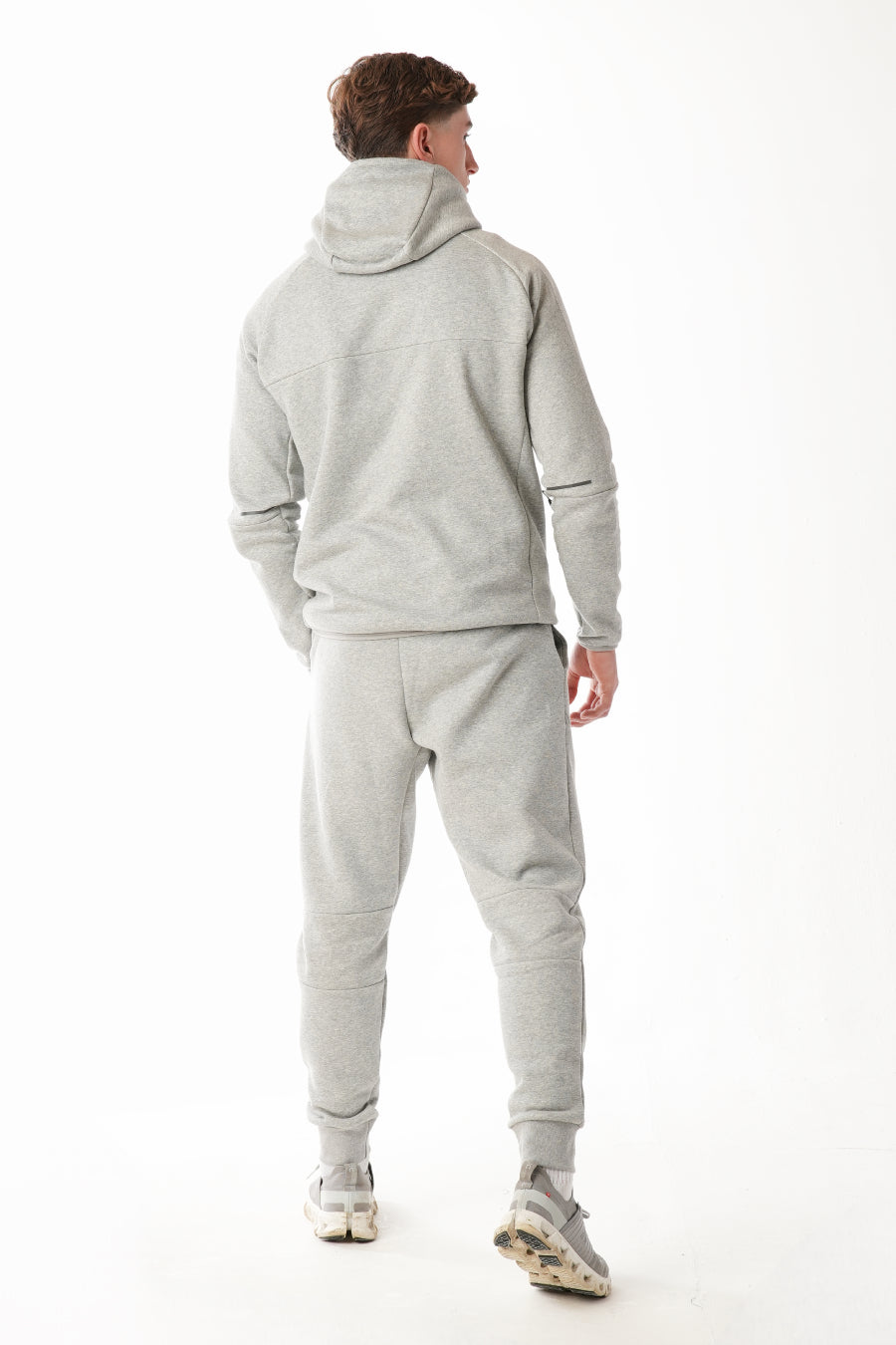 Person wearing a gray tracksuit on a white background