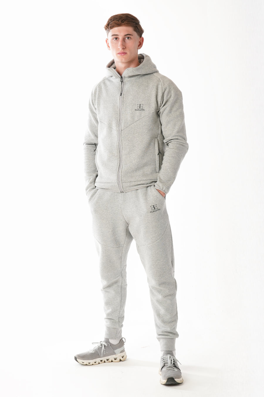Person wearing a gray tracksuit on a white background