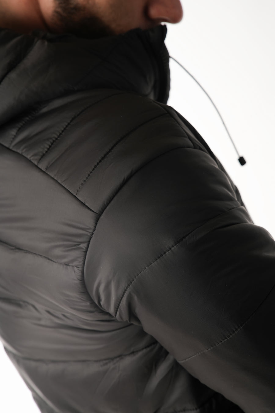 Close-up of a person wearing a dark gray puffer jacket on a white background