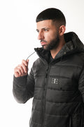 Man wearing a black puffer jacket with a brand logo on a white background