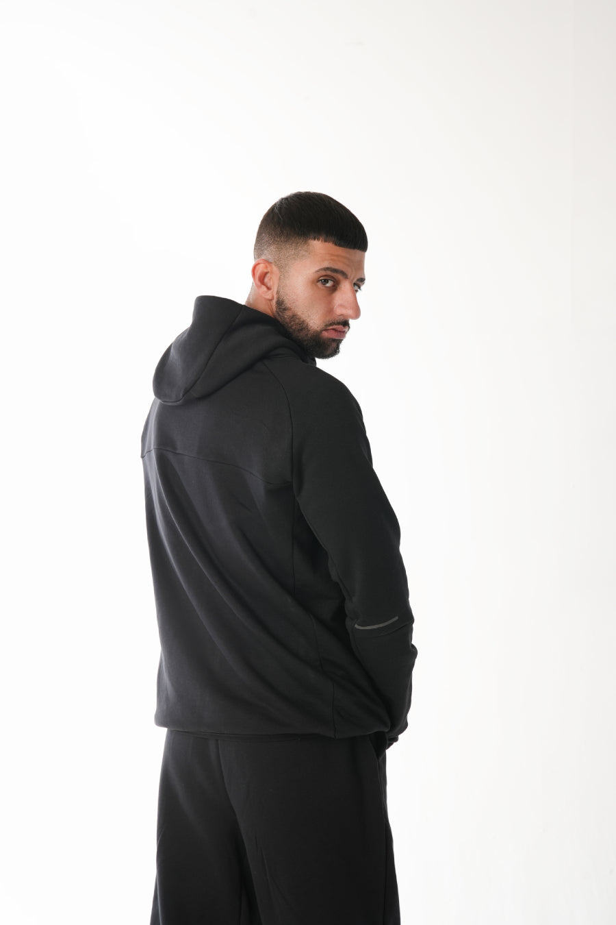 Man wearing a black hoodie and pants on a white background