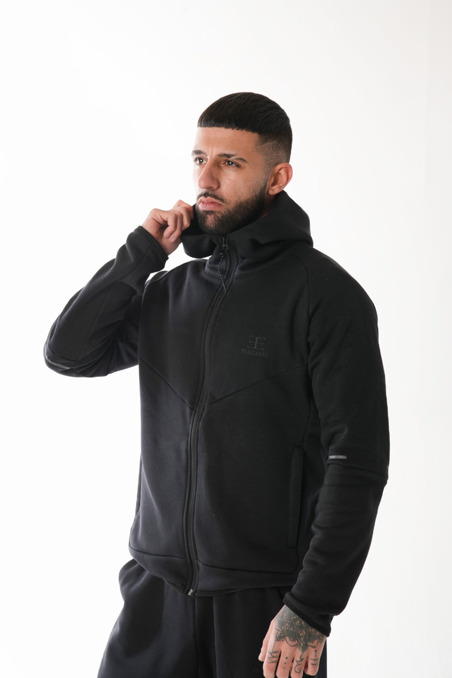 Man wearing a black tracksuit with a brand logo on a white background