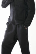 Black tracksuit worn by a person on a white background