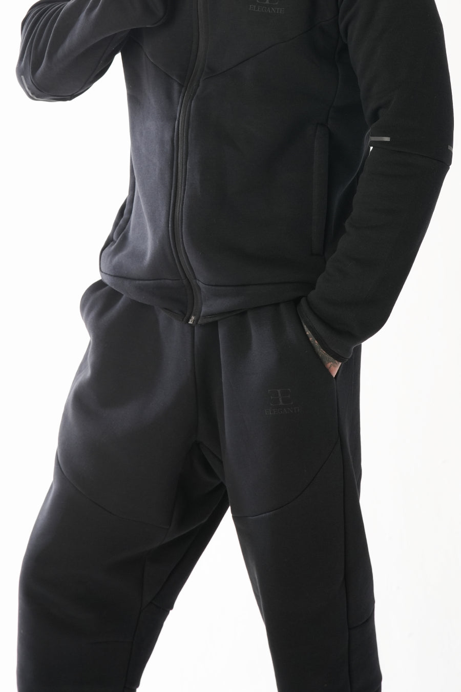 Black tracksuit worn by a person on a white background