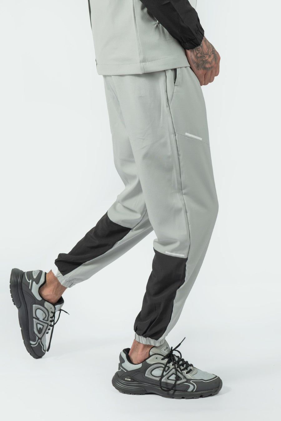 man wearing gray jogger pants with black accents on a white background