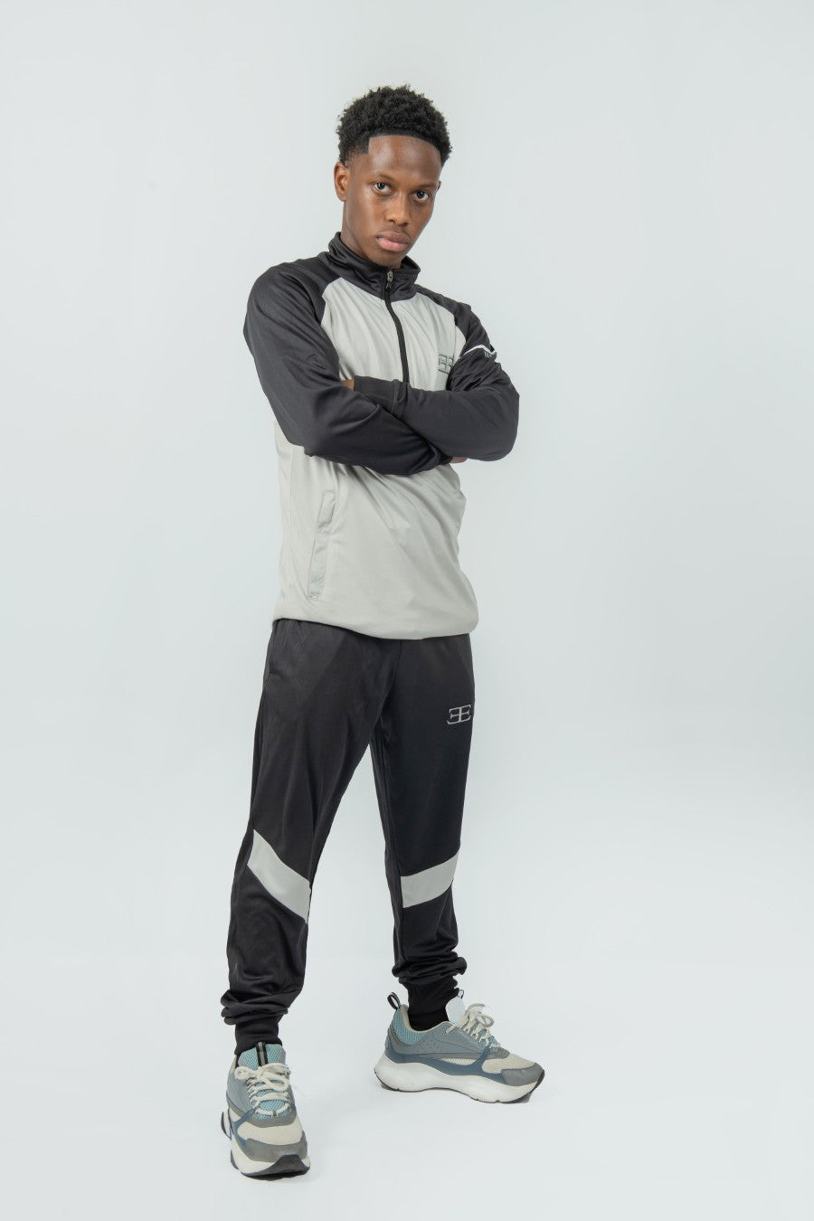 man wearing a gray and black tracksuit with a brand logo on a white background