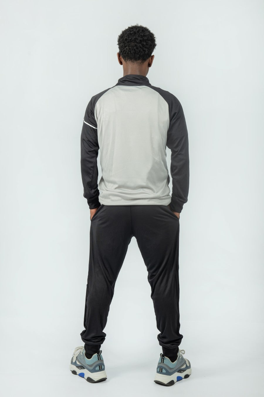 man wearing a gray and black tracksuit on a white background