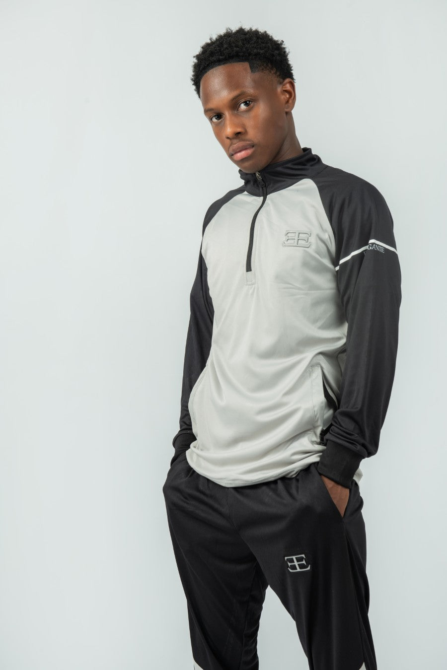 man wearing a black and gray sports outfit with a logo on a white background