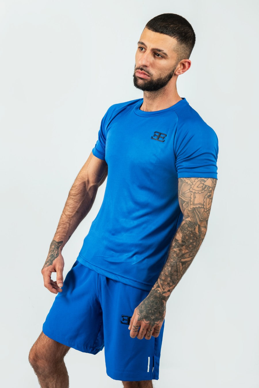 Man wearing a blue athletic shorts and tshirt outfit with a logo on a white background