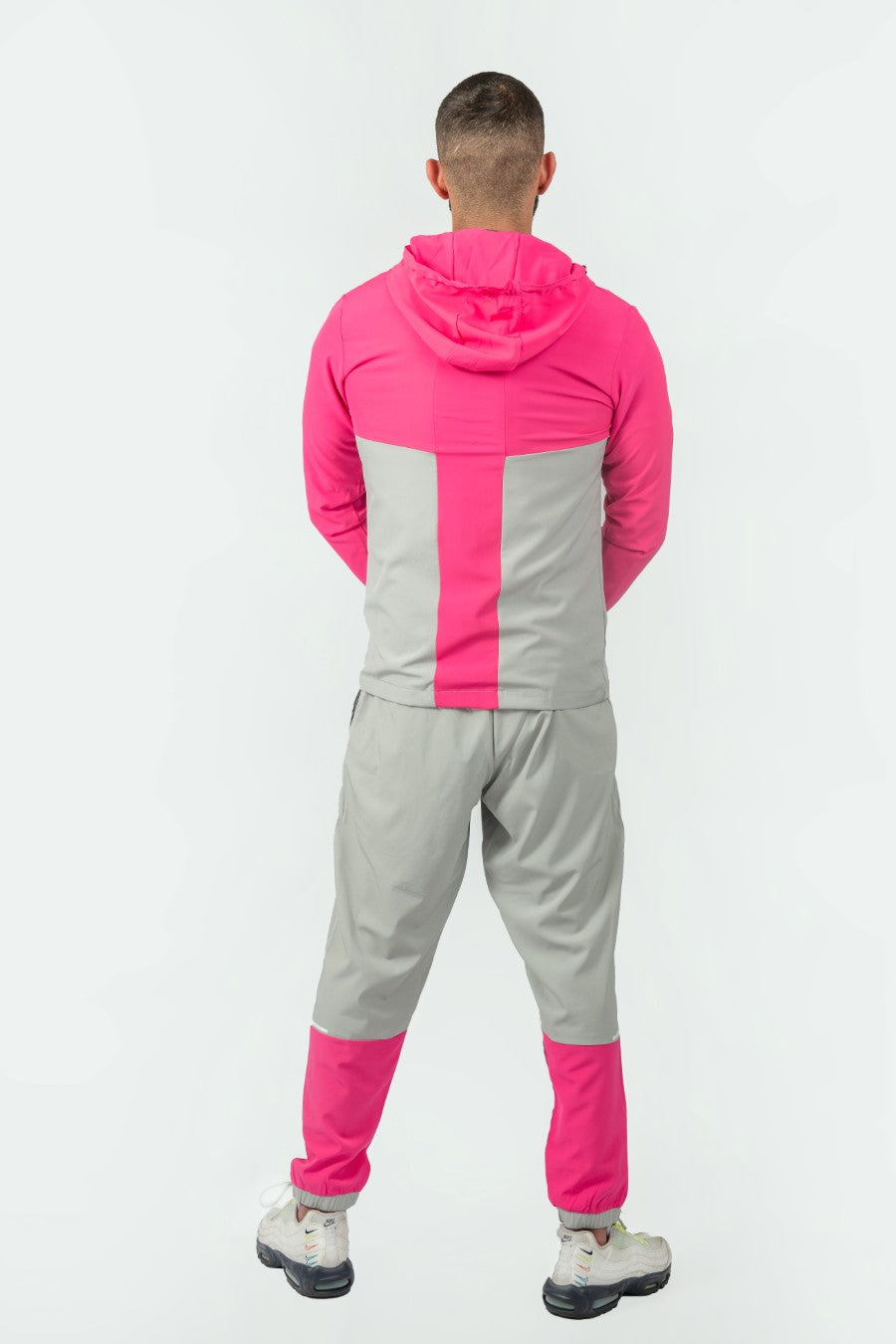man wearing pink and grey tracksuit with a elegante logo on a white background
