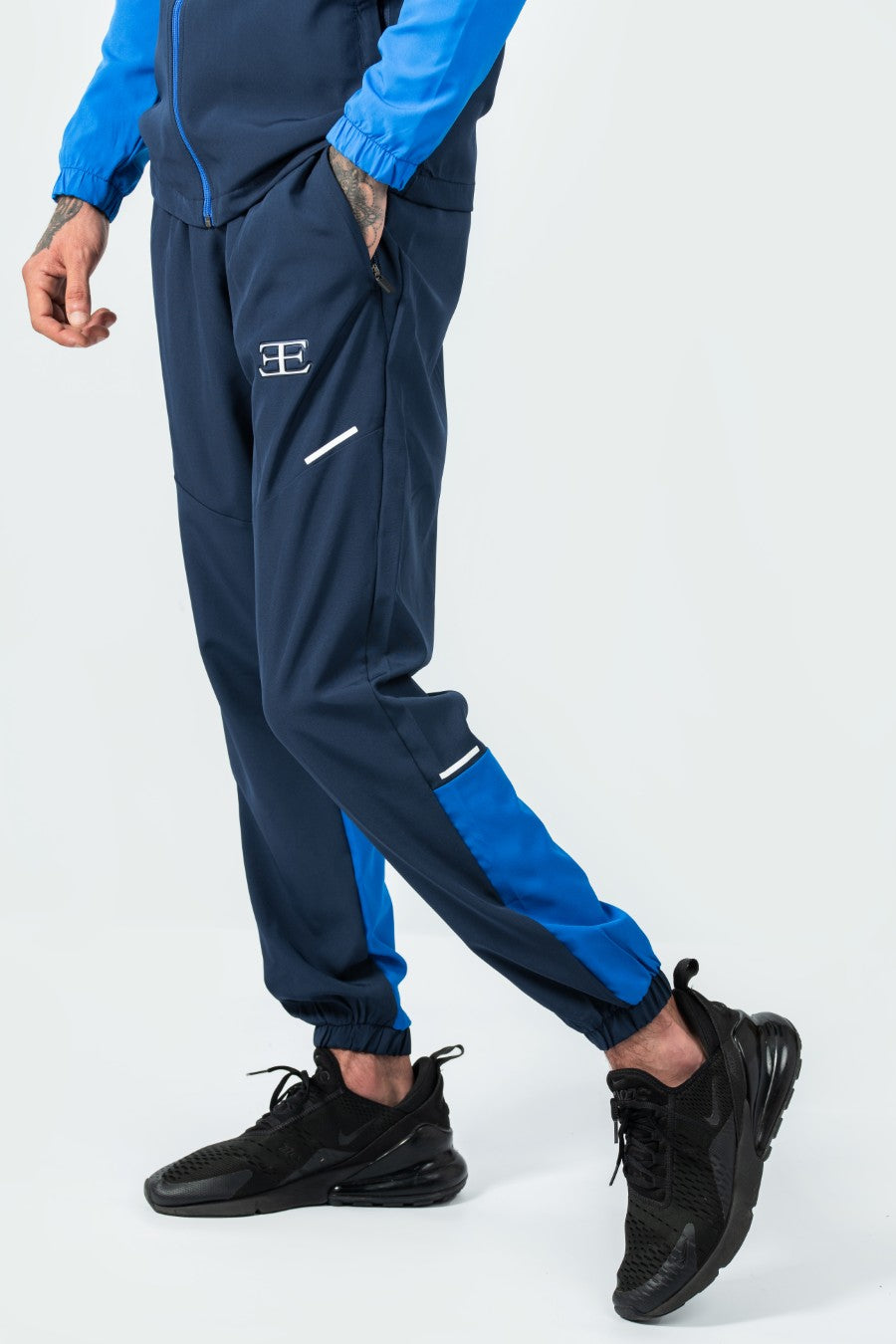 man wearing navy and blue tracksuit with a logo on a white background